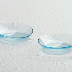 Two Contact Lenses with Water Droplets isolated on Grey Wet background