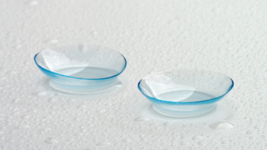 Two Contact Lenses with Water Droplets isolated on Grey Wet background